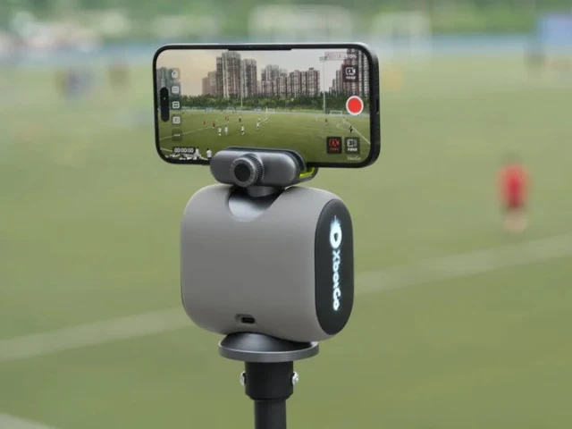 XbotGo Chameleon tracking mount holding an iPhone on a pole, recording a match on a field